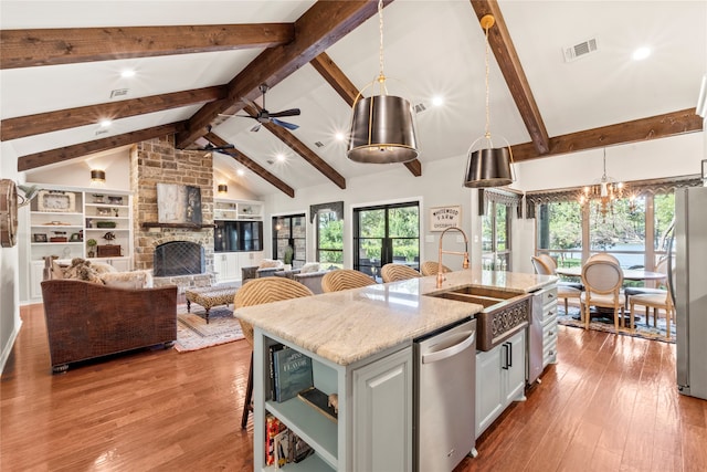 kitchen with white cabinets, stainless steel appliances, a fireplace, ceiling fan with notable chandelier, and light hardwood / wood-style floors