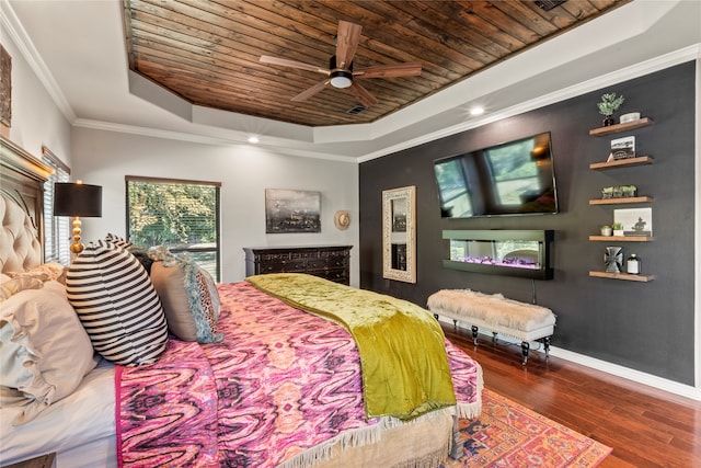 bedroom with dark wood-type flooring, wooden ceiling, a tray ceiling, ceiling fan, and ornamental molding