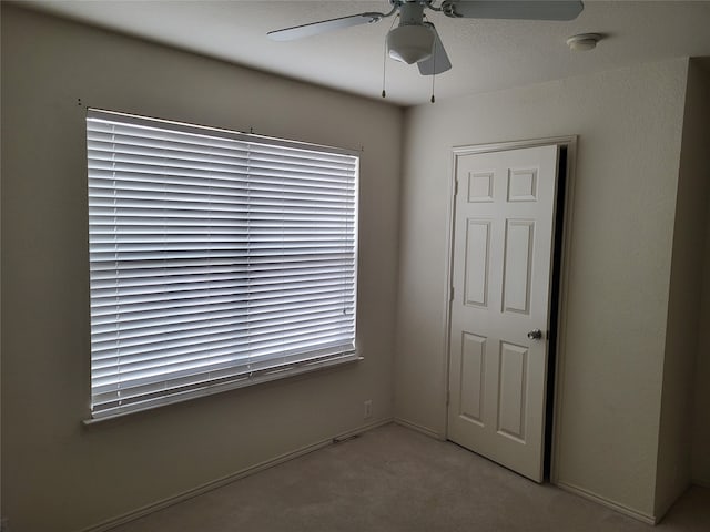 empty room with ceiling fan and light colored carpet