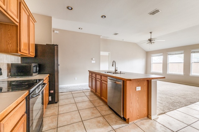 kitchen featuring sink, a kitchen island with sink, stainless steel appliances, light colored carpet, and vaulted ceiling