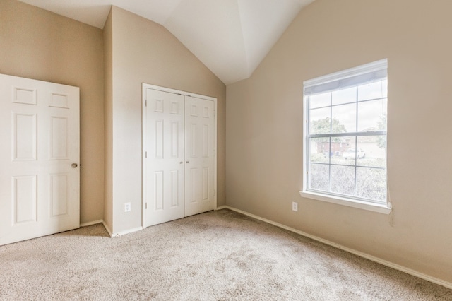 unfurnished bedroom featuring carpet, a closet, and vaulted ceiling