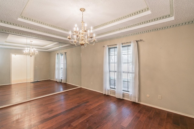 unfurnished room featuring a notable chandelier, a tray ceiling, wood-type flooring, ornamental molding, and a textured ceiling