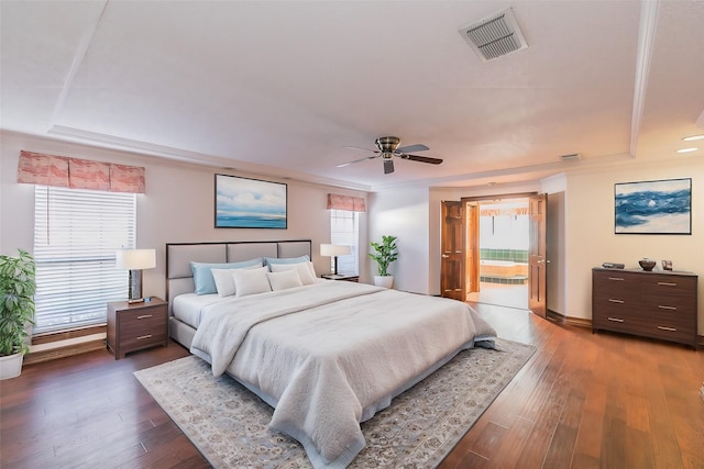 bedroom featuring dark wood-type flooring, ceiling fan, a raised ceiling, and access to outside