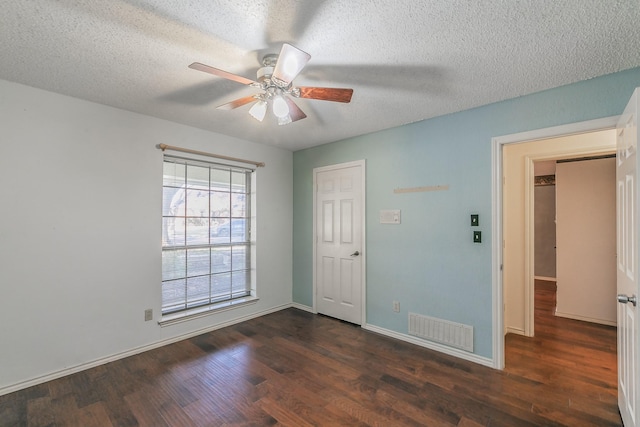 spare room featuring dark wood-type flooring, ceiling fan, and a textured ceiling