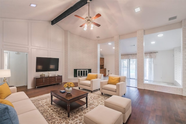 living room with ornate columns, hardwood / wood-style floors, vaulted ceiling with beams, ceiling fan, and a brick fireplace