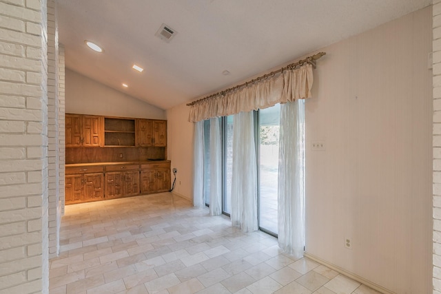 unfurnished living room with vaulted ceiling and light tile patterned floors