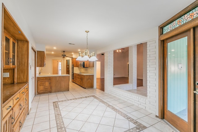 kitchen with pendant lighting, sink, light tile patterned floors, decorative columns, and kitchen peninsula