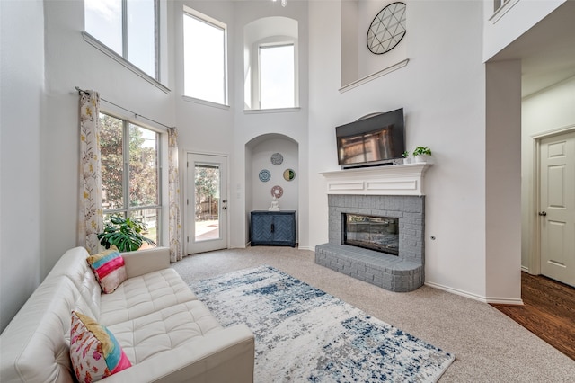 carpeted living room with a fireplace and a high ceiling