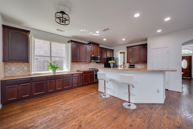 kitchen featuring appliances with stainless steel finishes, a center island, dark wood-type flooring, and a wealth of natural light