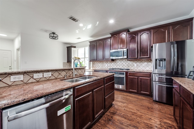 kitchen featuring light stone counters, dark hardwood / wood-style floors, sink, stainless steel appliances, and backsplash