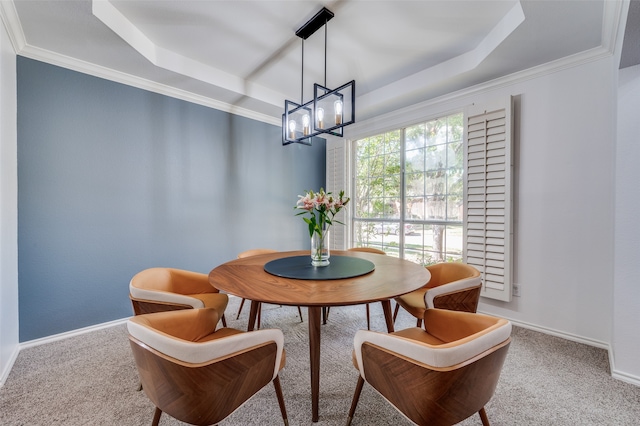 dining area with carpet floors, ornamental molding, a tray ceiling, and an inviting chandelier