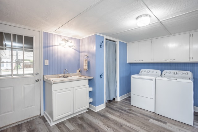 laundry area with cabinets, a textured ceiling, light hardwood / wood-style floors, sink, and washing machine and dryer