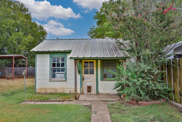 bungalow-style home with a front lawn and an outbuilding