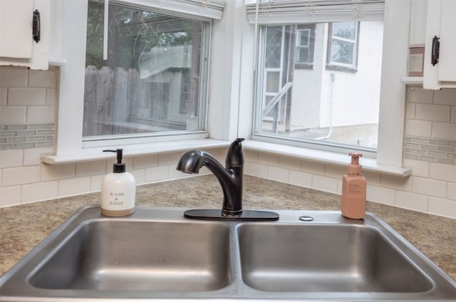 room details featuring tasteful backsplash, sink, and white cabinets