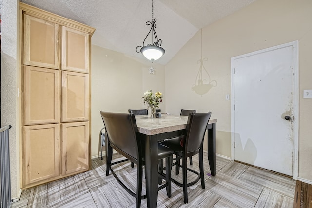 dining room with vaulted ceiling and a textured ceiling