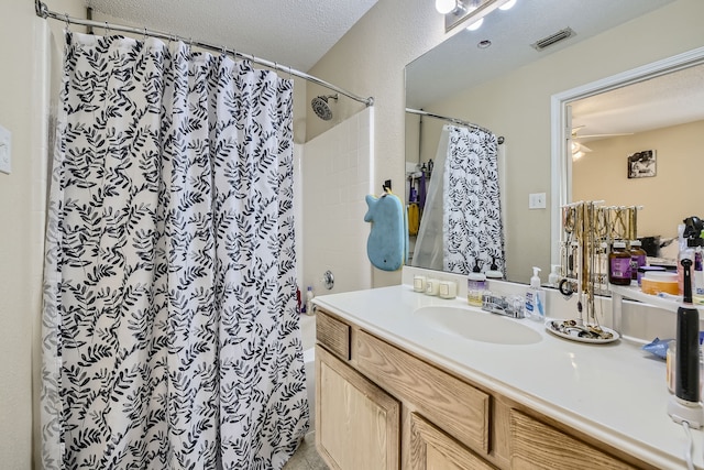 bathroom with a textured ceiling, vanity, ceiling fan, and a shower with curtain