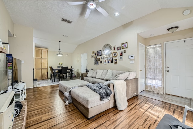 living room featuring wood-type flooring, a textured ceiling, lofted ceiling, and ceiling fan