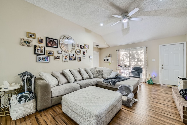 living room with a textured ceiling, wood-type flooring, vaulted ceiling, and ceiling fan