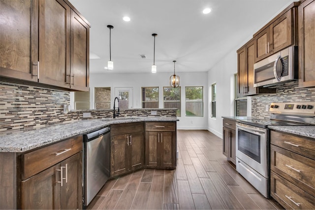 kitchen featuring sink, tasteful backsplash, decorative light fixtures, appliances with stainless steel finishes, and light stone countertops