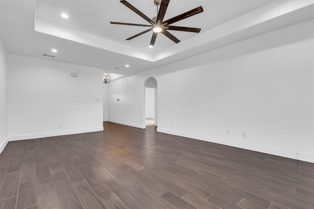 unfurnished room with dark wood-type flooring, ceiling fan, and a raised ceiling