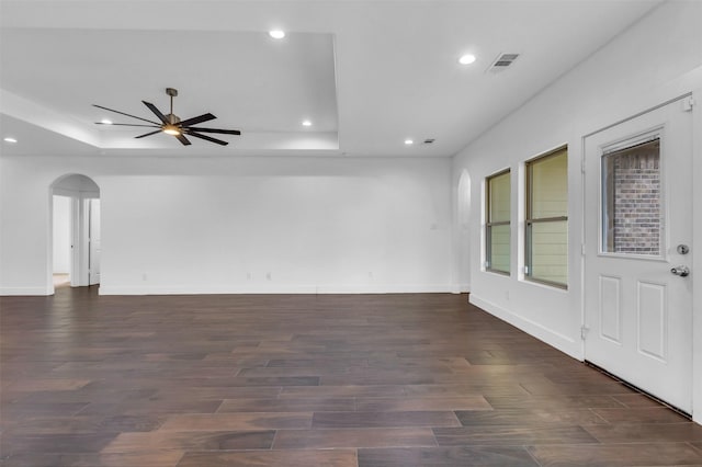 unfurnished room with a raised ceiling, ceiling fan, and dark hardwood / wood-style flooring