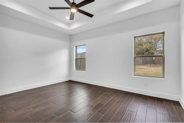 unfurnished room featuring ceiling fan, dark hardwood / wood-style floors, and a raised ceiling