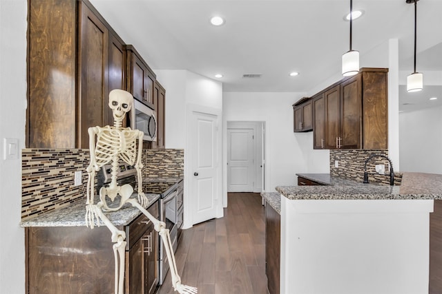 kitchen with pendant lighting, backsplash, dark wood-type flooring, and dark stone counters