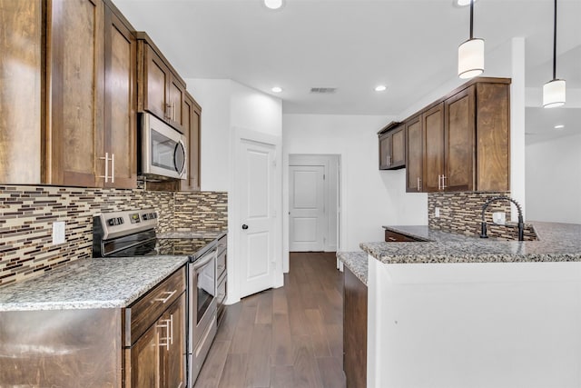 kitchen featuring dark hardwood / wood-style flooring, light stone countertops, stainless steel appliances, and hanging light fixtures