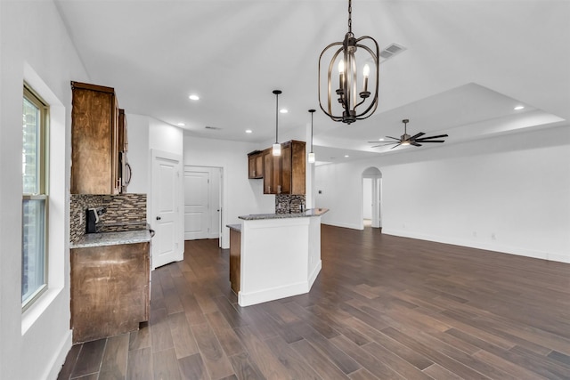 kitchen featuring hanging light fixtures, tasteful backsplash, light stone counters, and dark hardwood / wood-style flooring