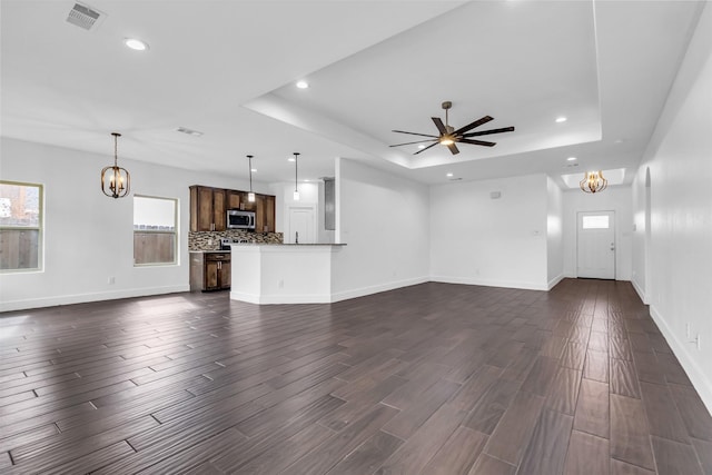 unfurnished living room with a healthy amount of sunlight, dark hardwood / wood-style floors, and a raised ceiling