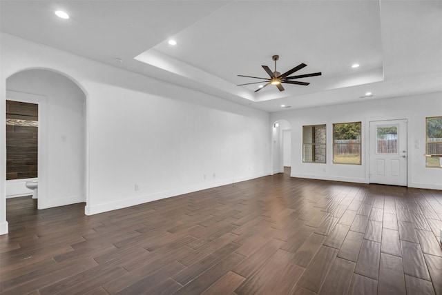 spare room featuring a raised ceiling, dark wood-type flooring, and ceiling fan