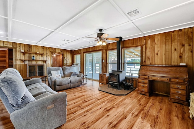 living room with ceiling fan, wood-type flooring, a wood stove, and coffered ceiling