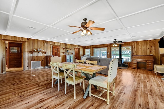 dining room featuring a wood stove, ceiling fan, and light hardwood / wood-style flooring