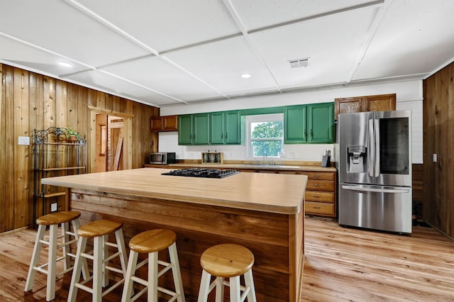 kitchen with a kitchen breakfast bar, black gas cooktop, stainless steel fridge, and wooden walls