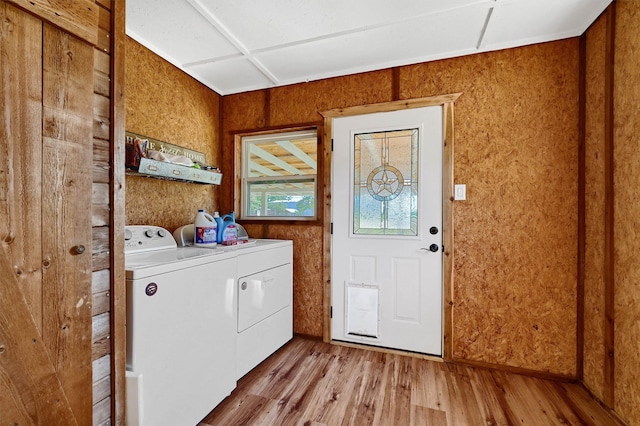 clothes washing area with washing machine and dryer and light hardwood / wood-style flooring