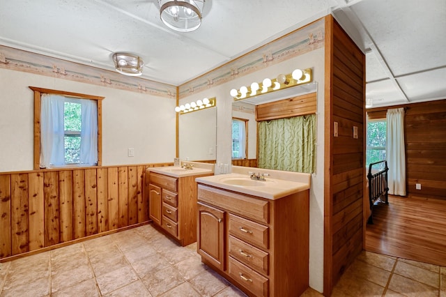 bathroom with wooden walls, vanity, and a textured ceiling