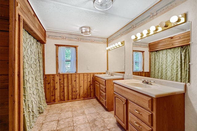 bathroom featuring wooden walls, vanity, and a textured ceiling