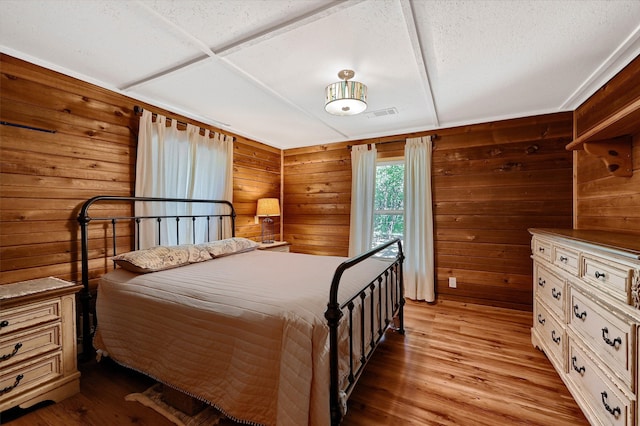 bedroom with wood walls and light hardwood / wood-style flooring