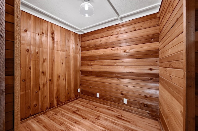 empty room with wooden walls and light hardwood / wood-style flooring