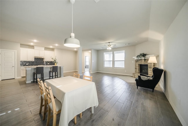 dining space featuring wood-type flooring, a fireplace, and ceiling fan