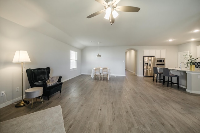 living room with wood-type flooring, lofted ceiling, sink, and ceiling fan