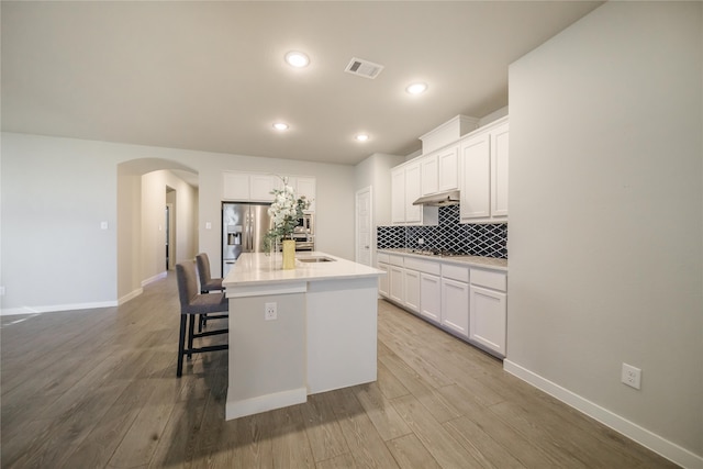 kitchen featuring light hardwood / wood-style flooring, white cabinets, a center island with sink, and stainless steel fridge with ice dispenser