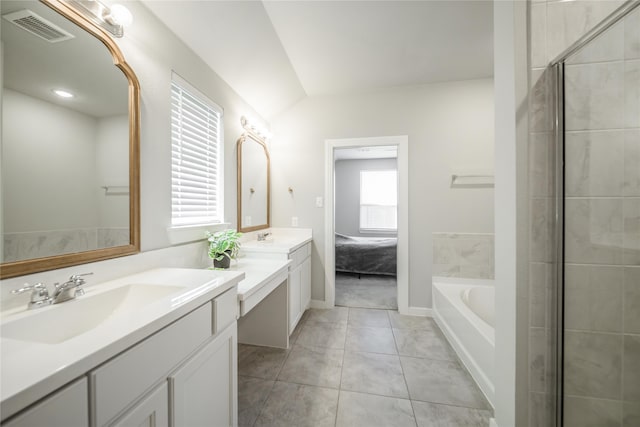 bathroom featuring independent shower and bath, vanity, vaulted ceiling, and tile patterned floors