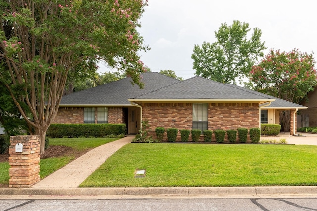 single story home with a front lawn, a shingled roof, and brick siding