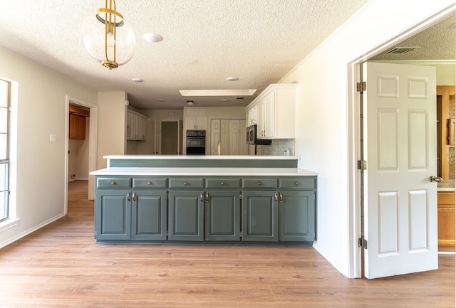 kitchen featuring white cabinets, light hardwood / wood-style floors, and hanging light fixtures