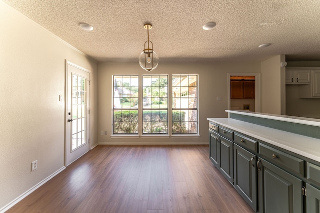 interior space with a textured ceiling, gray cabinetry, dark hardwood / wood-style floors, and pendant lighting