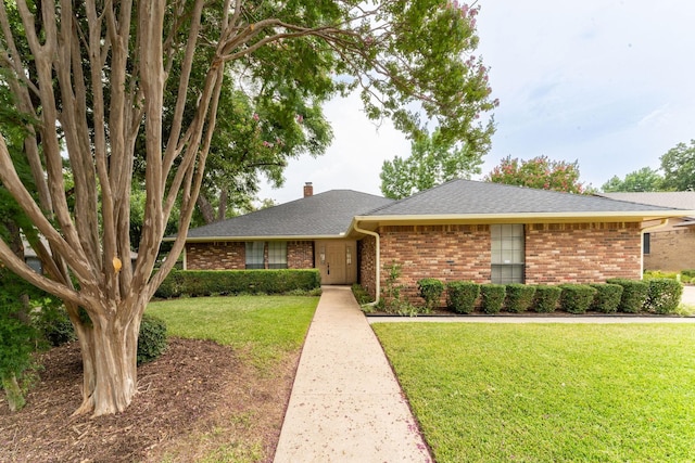 ranch-style home featuring brick siding, a chimney, and a front lawn