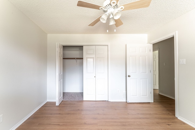 unfurnished bedroom featuring ceiling fan, a textured ceiling, light wood-type flooring, and a closet