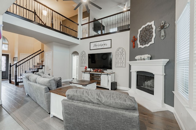 living room featuring wood-type flooring, a towering ceiling, and ceiling fan