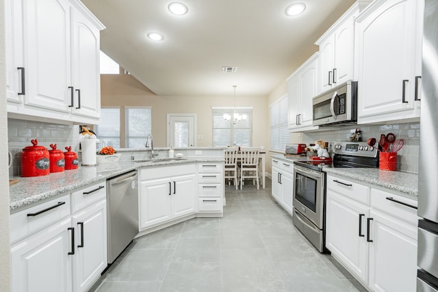 kitchen with sink, white cabinets, hanging light fixtures, an inviting chandelier, and appliances with stainless steel finishes